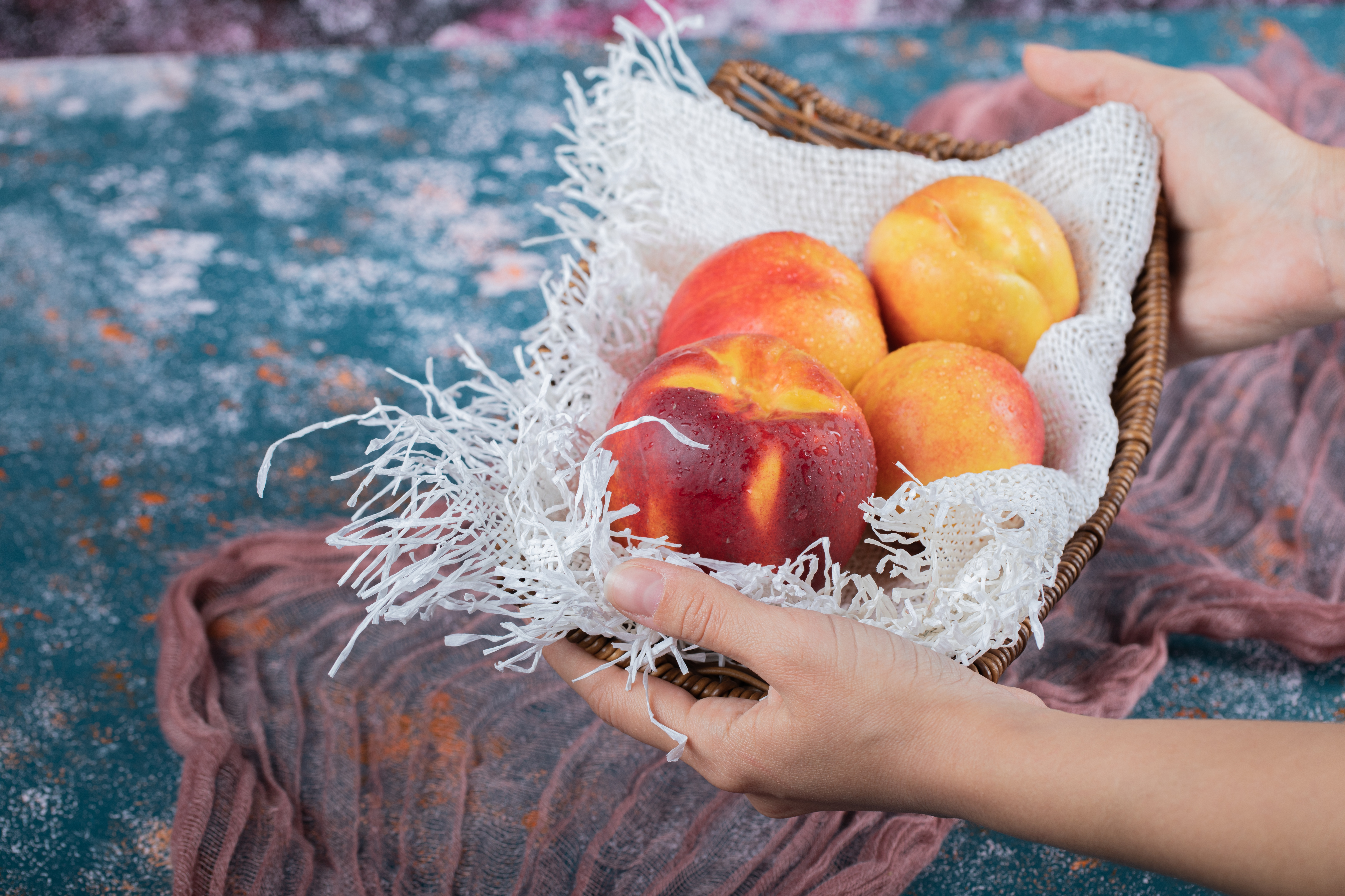 Hands holding a basket of fresh peaches